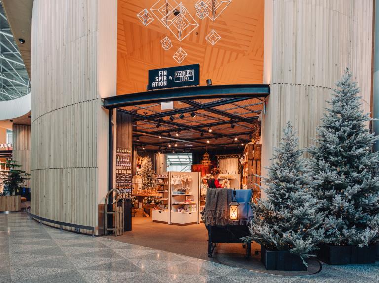 Finspiration-myymälän sisäänkäynti Helsinki-Vantaan lentoasemalla, oven vieressä huurteisia kuusia
